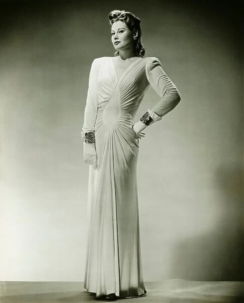Sophisticated woman in evening gown posing in studio, (B&W), portrait