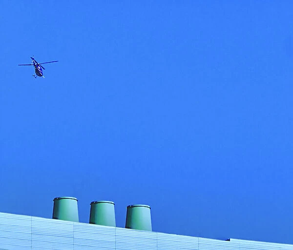 Sortie. A color photo of a helicopter flying over a commercial building