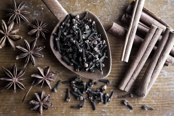 Spices, cloves, star anise and cinnamon sticks with wooden spoon on rustic wood