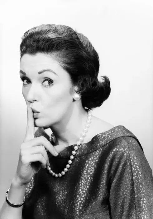 Framed Print : Studio portrait of mature woman holding finger to lips Framed Print : Studio portrait of mature woman holding finger to lips