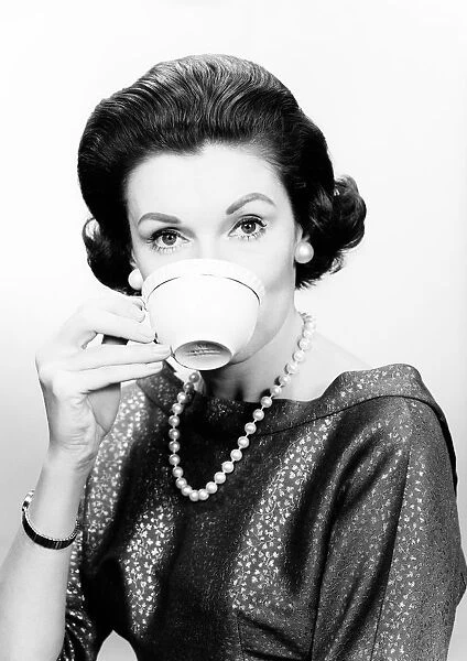 Studio portrait of mid adult woman drinking from cup