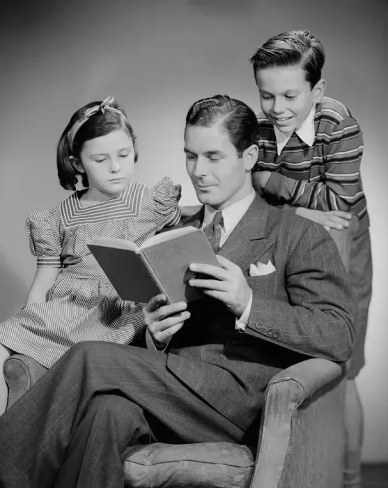 Framed Print : Studio shot of father with two children (10-11) reading book