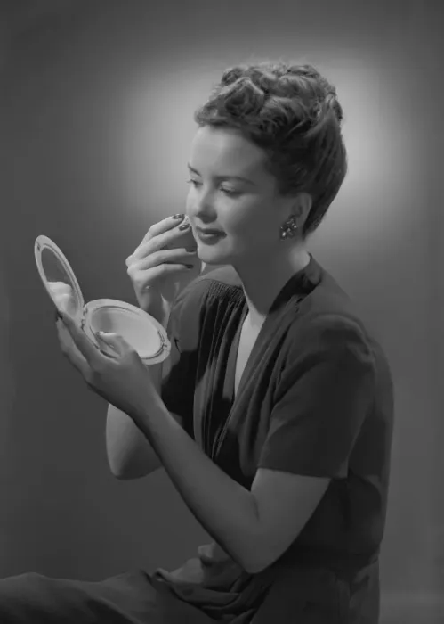 Framed Print : Studio shot of young woman applying make-up Framed Print : Studio shot of young woman applying make-up