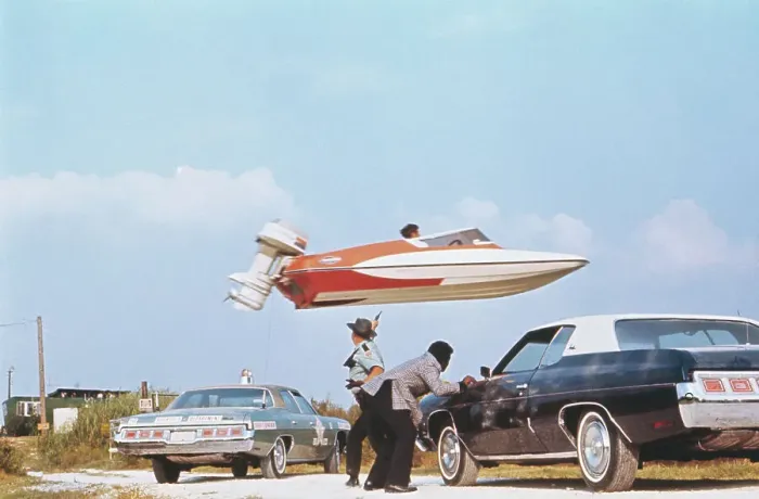 Framed Print : Stuntman Jumping a Speedboat over Cars Framed Print : Stuntman Jumping a Speedboat over Cars