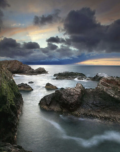 Sunset light rocky coast storm clouds sea