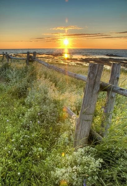 Sunset Over Water And A Fence Along The Shoreline
