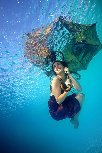 Sunshower. An underwater photo of a young woman with an umbrella looking up