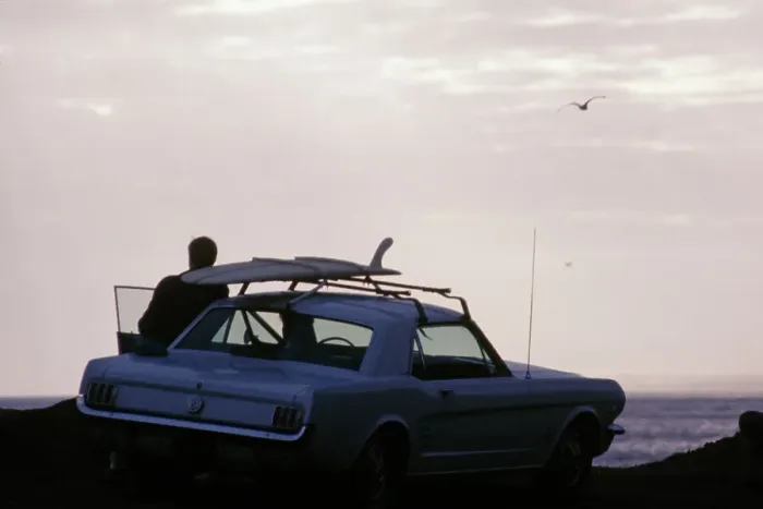 Framed Print : Surf Car. A man leaning against a car with a surfboard mounted on the roof Framed Print : Surf Car. A man leaning against a car with a surfboard mounted on the roof