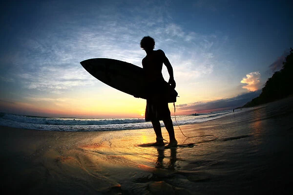 Surfer on beach at sunset