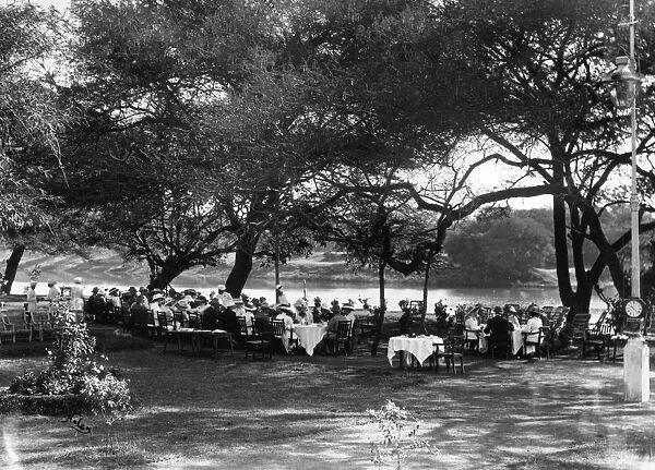 Tea Party. circa 1900: People seated at tea tables in the shade of trees