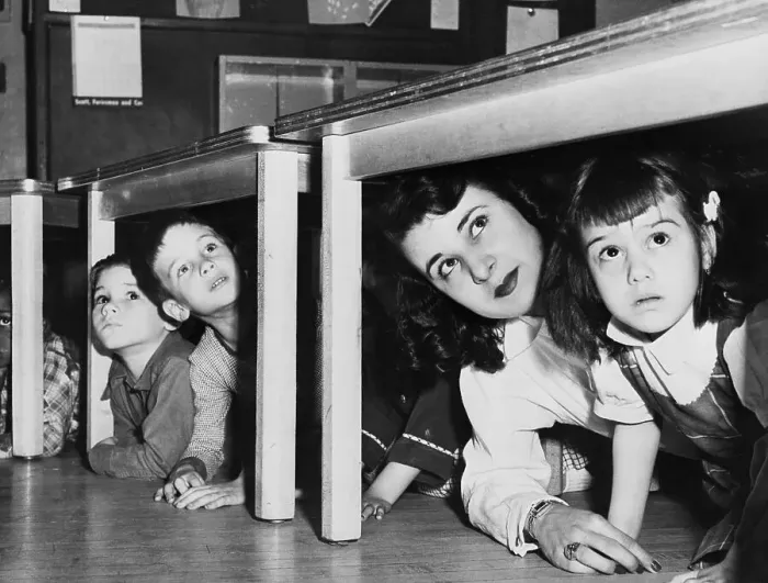 Framed Print : Teacher And Children Crouching Under Table
