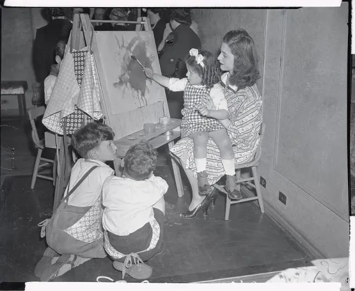 Framed Print : Teacher Holding Child Making Painting Framed Print : Teacher Holding Child Making Painting
