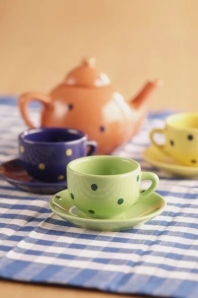 Teapot, cups and saucers on a chequered table cloth