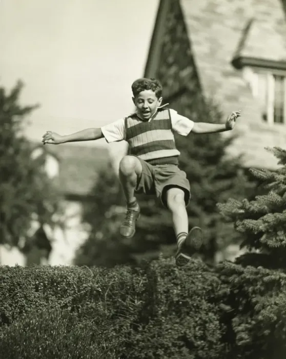 Framed Print : Teenage boy (13-14) leaping over hedge, (B&W), low angle view Framed Print : Teenage boy (13-14) leaping over hedge, (B&W), low angle view