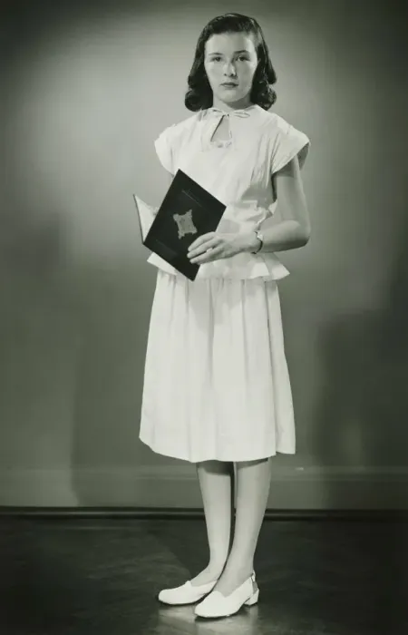 Framed Print : Teenage girl (13-14) in white dress standing in studio with open book, (B&W) Framed Print : Teenage girl (13-14) in white dress standing in studio with open book, (B&W)