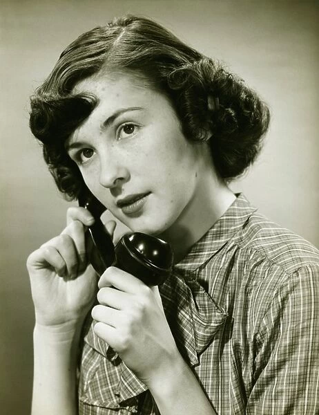 Teenage girl (16-17) on phone posing in studio, (B&W), portrait