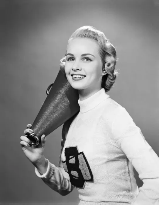 Framed Print : Teenage girl wearing cheerleader sweater holding megaphone over shoulder