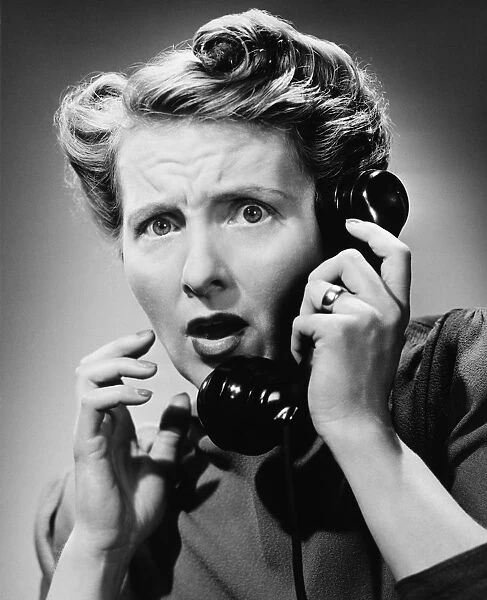 Terrified woman talking on phone, (B&W), portrait