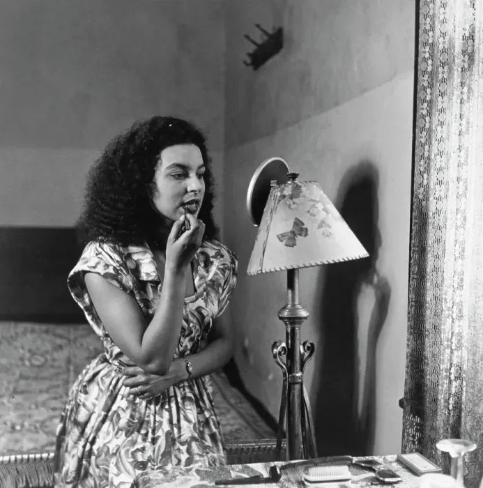 Framed Print : Tiger Bay. A woman applying lipstick in front of a mirror at home in Tiger