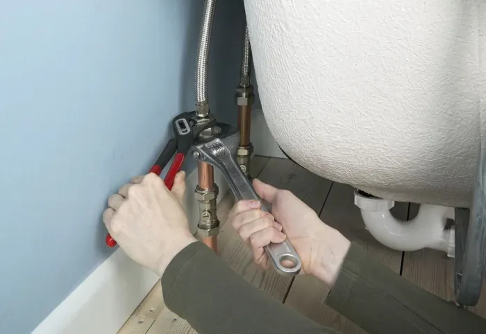 Framed Print : Tightening flexible connectors attached to a bath with an adjustable spanner and grips, close up