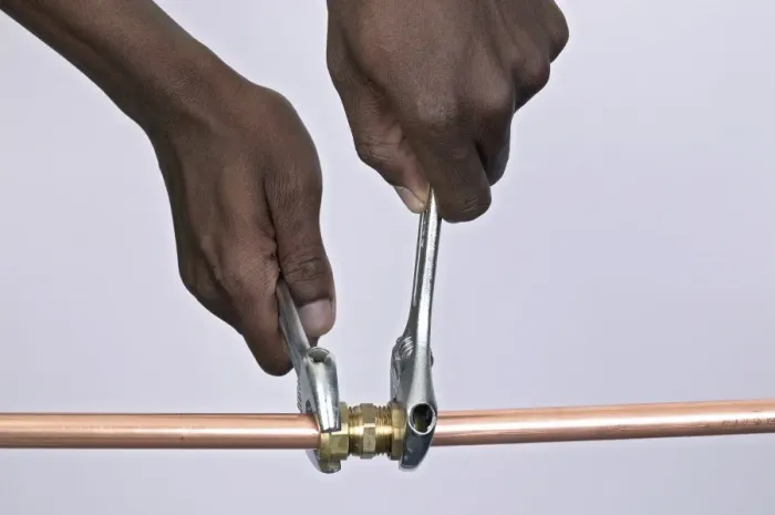 Framed Print : Tightening nuts to a compression joint attached to copper pipes using adjustable spanners Framed Print : Tightening nuts to a compression joint attached to copper pipes using adjustable spanners