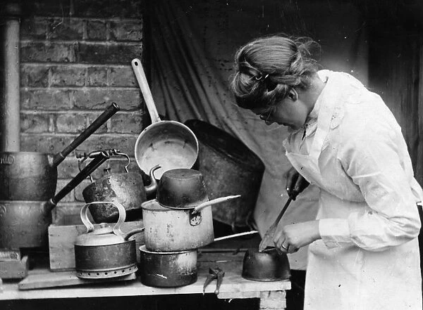 Tinkering. circa 1930: A woman mending pots and pans