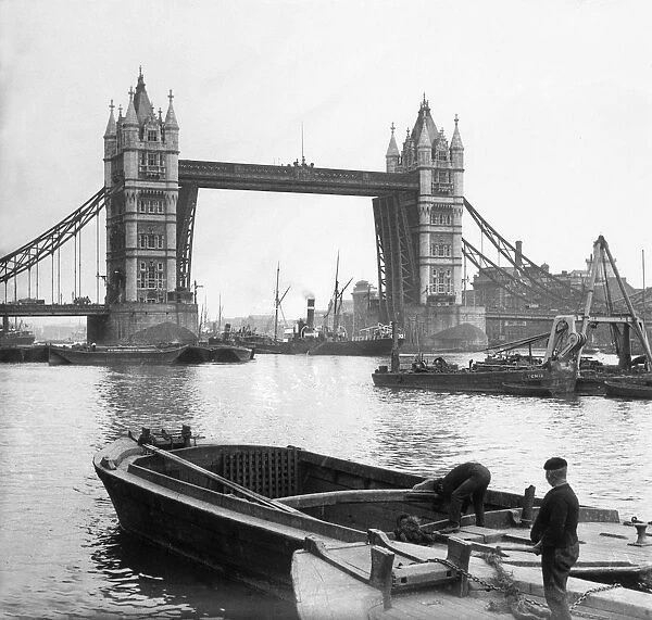 Tower Bridge. circa 1905: Boatmen on the River Thames near Tower Bridge