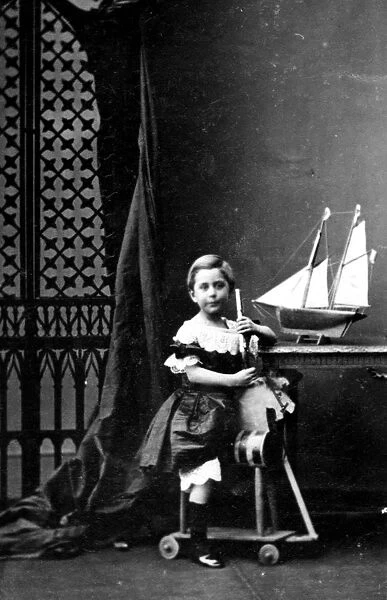 Toy Horse. A young girl sitting on a wooden horse with a toy boat on the desk next to her
