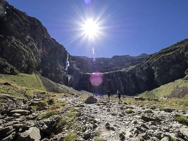 Trekkers walking along the cirque of Gavarnie. Hautes Pyrenees. France. World Heritage by UNESCO, the great waterfall