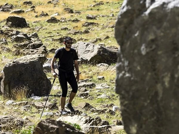 Tripper with rucksack and stick crossing a way of high mountain in the pyrenees, Gavarnie