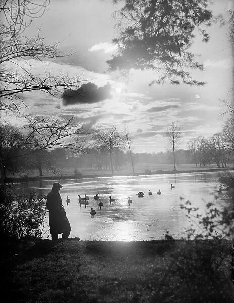 Twilight. 8th December 1933: A solitary figure comtemplates the setting sun over a lake
