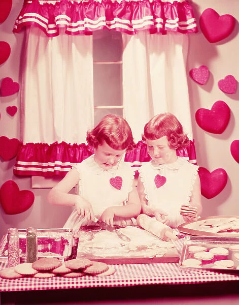 Twin girls in kitchen, baking Valentine cookies