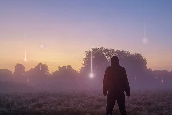 A UFO, supernatural concept. A hooded figure with his back to the camera