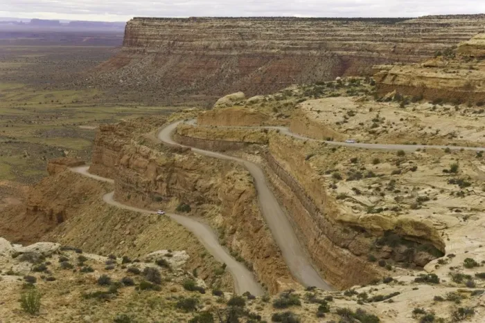 Framed Print : USA, Utah, cars on dirt road climbing plateau in desert, autumn