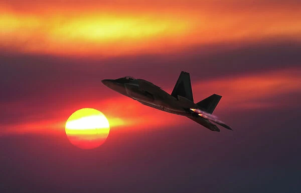 A USAF Lockheed Martin F-22A Raptor stealth fighter flying into the sunset