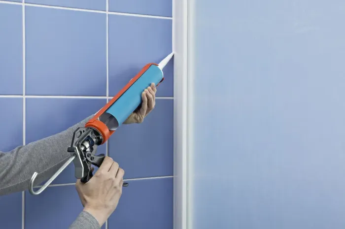 Framed Print : Using a sealant dispenser to seal outside edge of a shower screen Framed Print : Using a sealant dispenser to seal outside edge of a shower screen