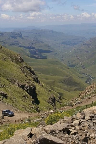 A vehicle driving along a trail through the hills of the Sani Pass, Drakensberg Park, KwaZulu-Natal, South Africa