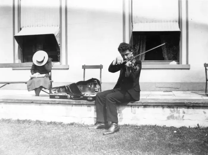 Framed Print : Violinist. circa 1908: A youth playing the violin, while sitting on a wall outsde a house Framed Print : Violinist. circa 1908: A youth playing the violin, while sitting on a wall outsde a house