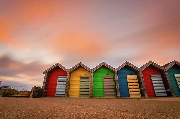 Vivid coloured beach huts at sunset