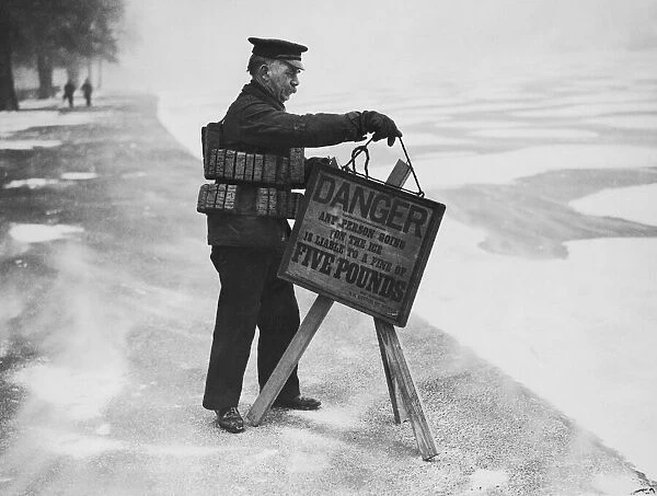 Warning And Fine. A man employed by the Royal Humane Society placing a sign of danger