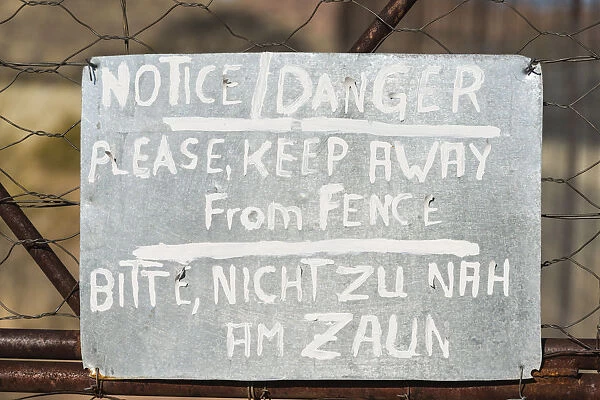 Warning sign in English and German on the fence of a predator enclosure, Namibia