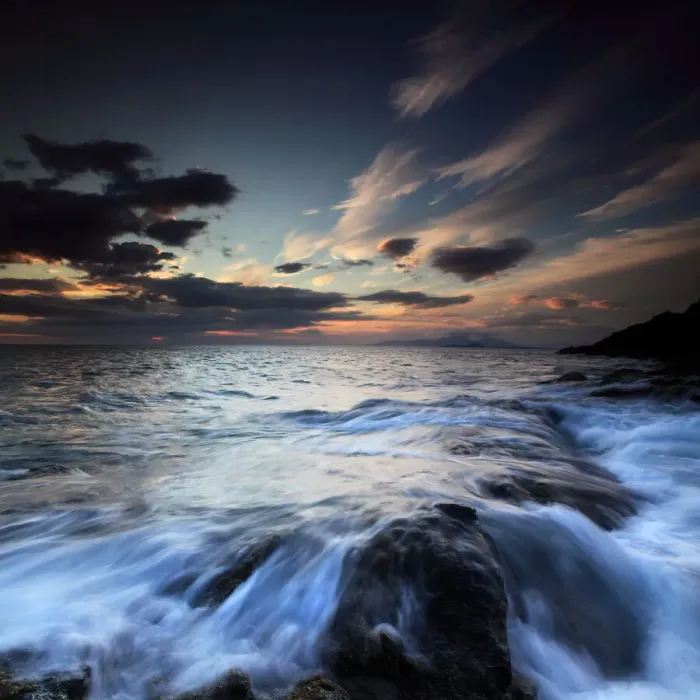 Framed Print : Water flowing over rocks on sea at sunset