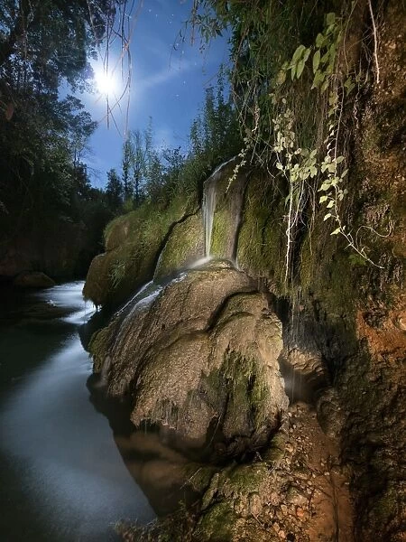 Waterfall in a ravine in the moonlight fills