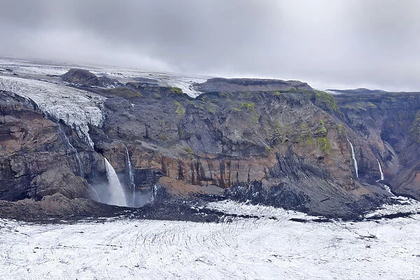 Waterfalls cascading into the canyon below Hoefoabrekkajoekull glacier, Pakgil, Iceland