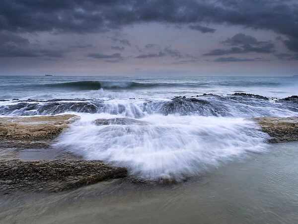 Wave jumping rocks in storms at sea at dawn