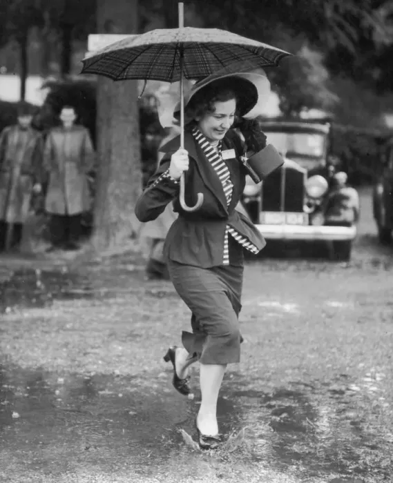 Framed Print : Wet Feet. Circa 1945, A smartly dressed woman with an umbrella splashes