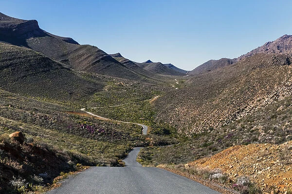 The winding road climbing up the remote and rugged wilderness area of the Cederberg mountains in the distance. Western Cape Province, South Africa