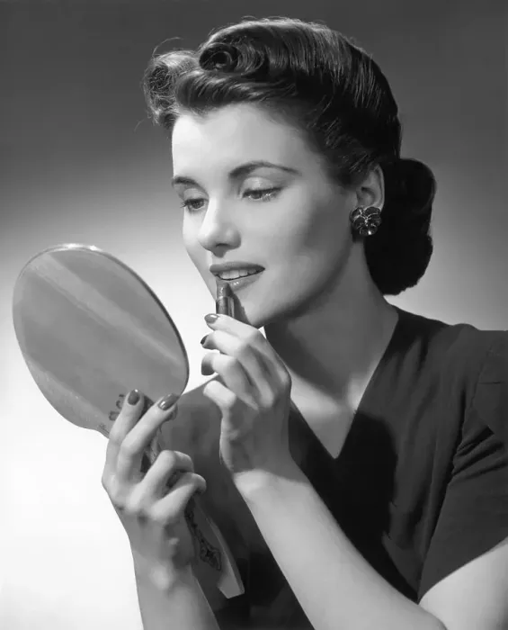 Framed Print : Woman applying lip-stick looking in hand-held mirror Framed Print : Woman applying lip-stick looking in hand-held mirror