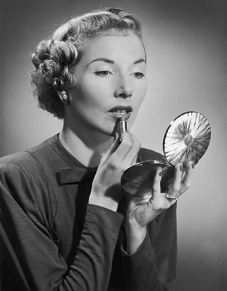 A woman applying her lipstick with the aid of a powder compact, circa 1955. (Photo by H. Armstrong Roberts / Retrofile / Getty Images)