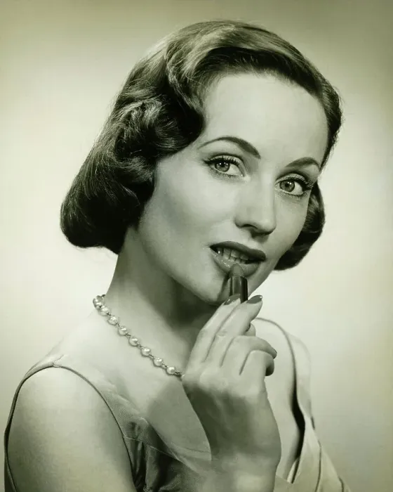 Framed Print : Woman applying lipstick in studio, (B&W), portrait